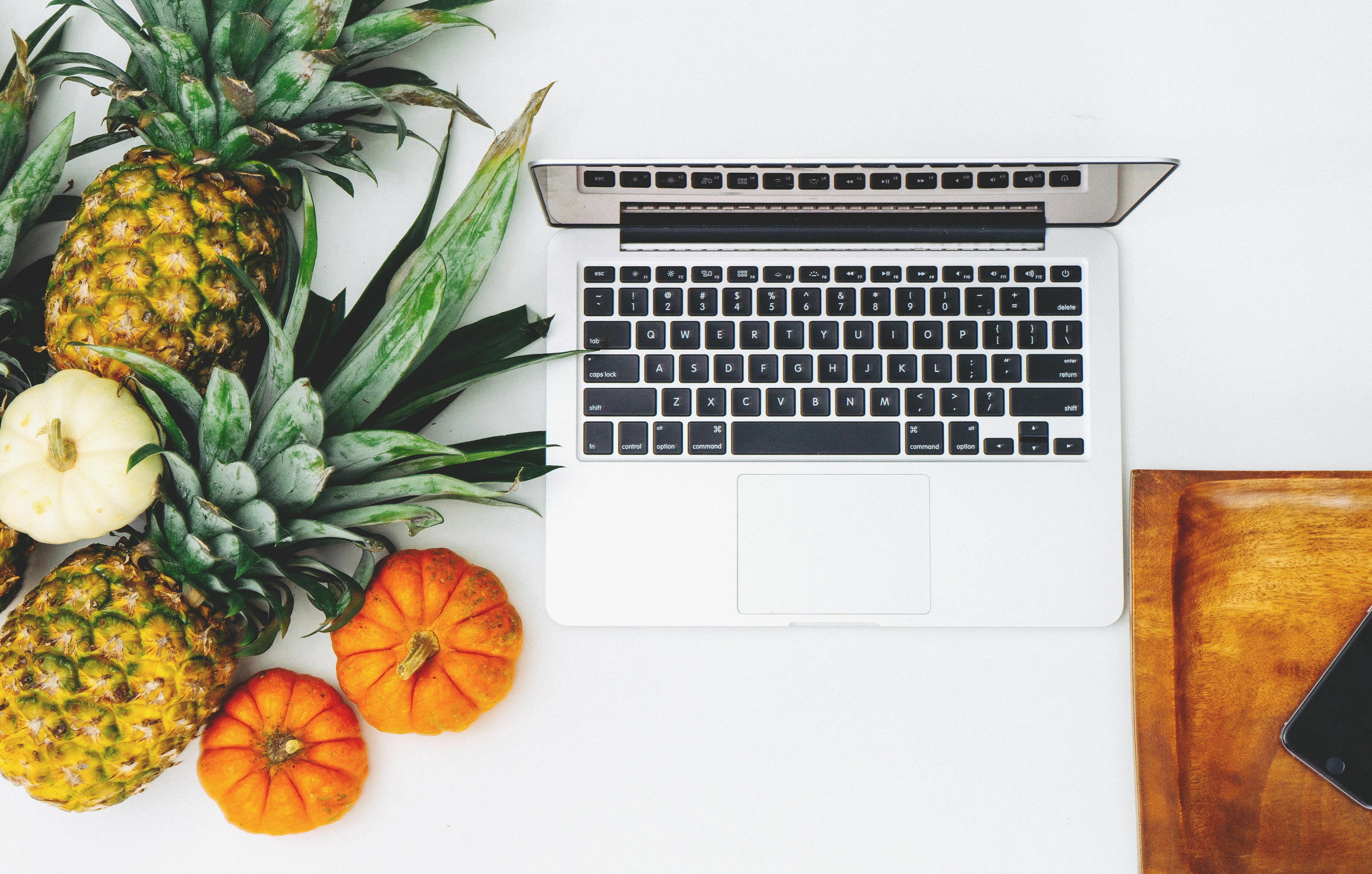 Laptop neben Ananas und Kürbis