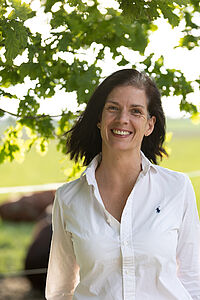 Foto unserer Referentin Daniela Lang: Sie hat schulterlanges, glattes, braunes Haar und lächelt in die Kamera. Sie trägt eine weiße Bluse