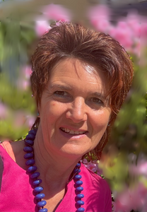 Foto unserer Referentin Simone Wanzek-Weber: Sie lächelt, hat braunes kurzes Haar und trägt eine blau Perlenkette und ein pinkes T-Shirt