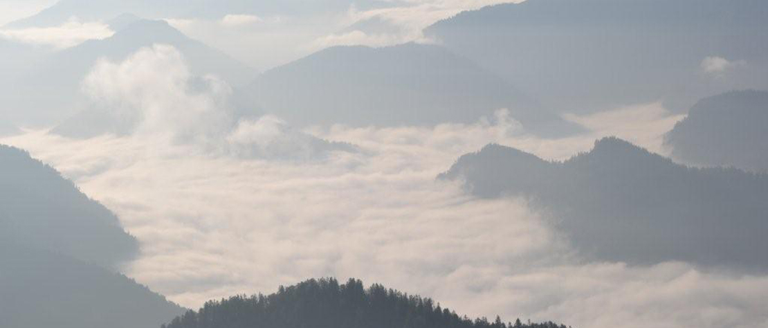 Blick von einem Berggipfel in ein Wolkenmeer mit Bergspitzen